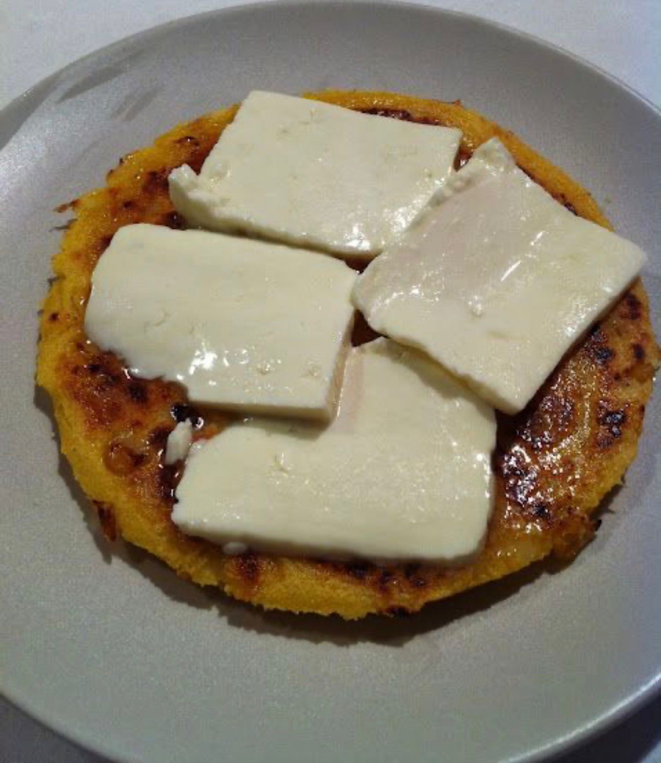 Arepa hecha con choclo con topping de queso fresco.
